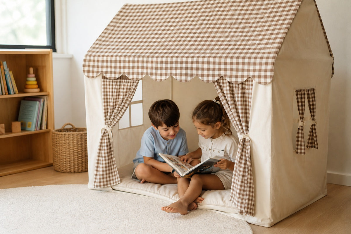 Two siblings reading together inside a gingham CampCuddle playhouse
