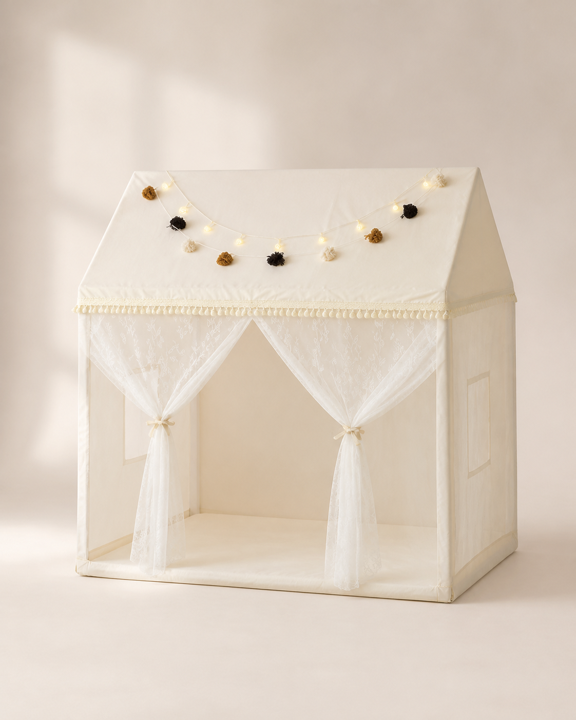 Cream house-frame kids play canopy with pom-pom garland on a warm studio background